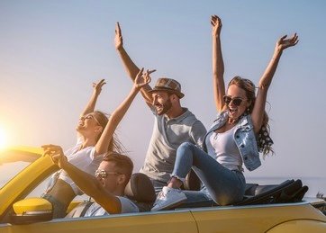 The friends are traveling by a yellow cabriolet